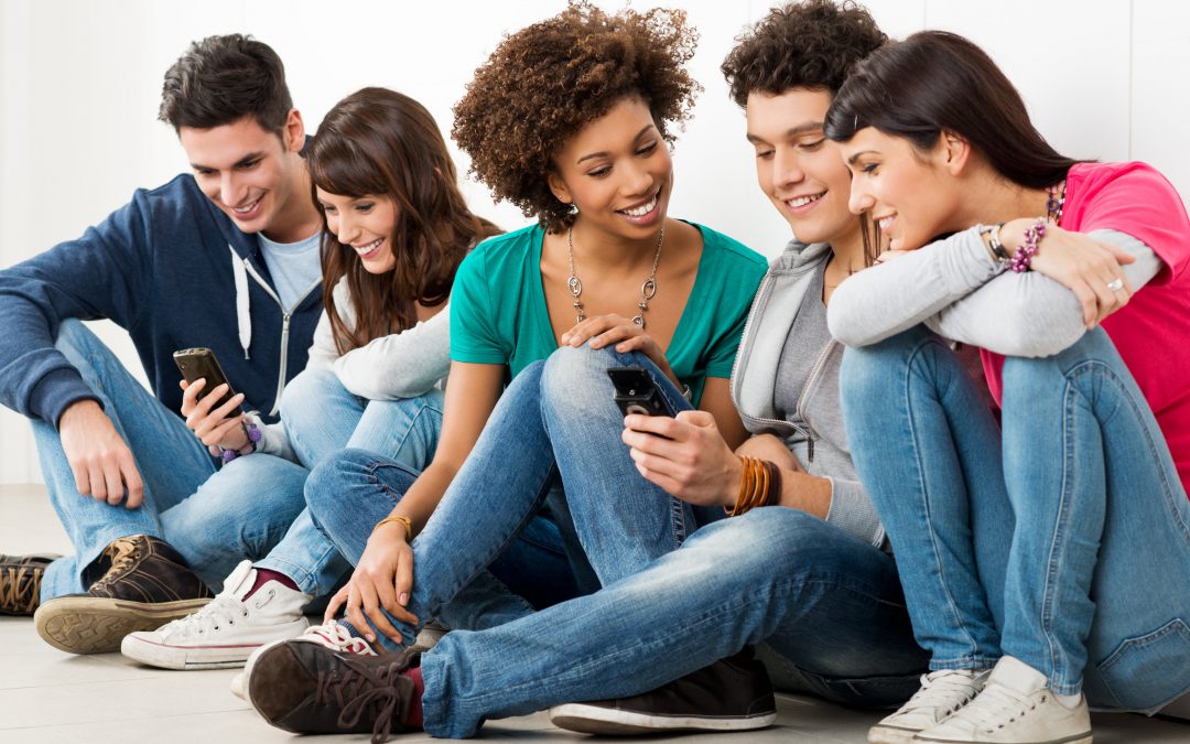 Group Of Happy Young Friends Looking At Cell Phone